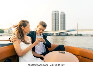 Caucasian couple relax and enjoy urban outdoor lifestyle travel city on luxury private boat yacht sailing in the river with celebrating holiday event drinking champagne together on summer vacation.