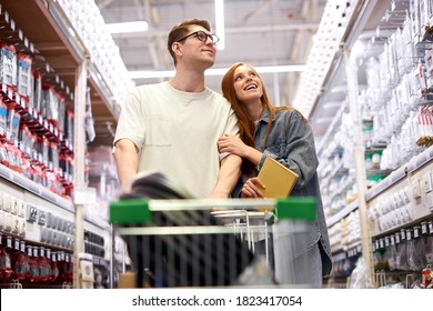 Caucasian Couple Shopping Together, Use Information Book And Discuss, Going To Equip New House, Buy Necessary Things For Home