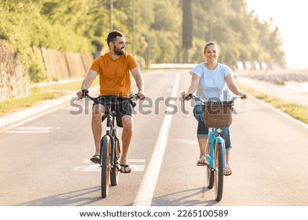 Caucasian couple taking pleasure in the ride on beach cruiser bikes, pedaling on a wonderful route near the sea