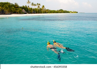 Caucasian Couple Of Tourists Snorkel In Crystal Turquoise Water Near Maldives Island