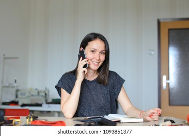 Caucasian craftswoman speaking by smartphone at leather atelier and making handmade notebook and wallets, tools and materials on table. Concept of home business, handicraft and hobby. - Powered by Shutterstock