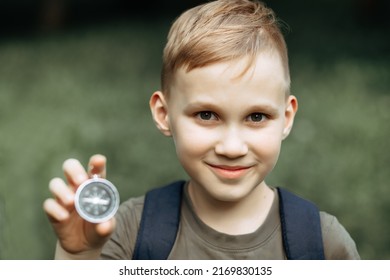 Caucasian Cute Kid Boy With A Backpack Travels With A Compass. Child Boy Scout Holding In A Hand Compass In The Forest During A Hike. Children Summer Outdoor Activity