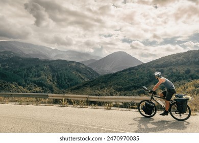 Caucasian cyclist solo bicycle touring around mountains in summer with scenic mountain rage background outdoors. - Powered by Shutterstock