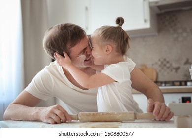 Caucasian dad and daughter with down syndrome, funny dad and girl hug and cook together in the kitchen in a bright kitchen, life style and father's day, single parents