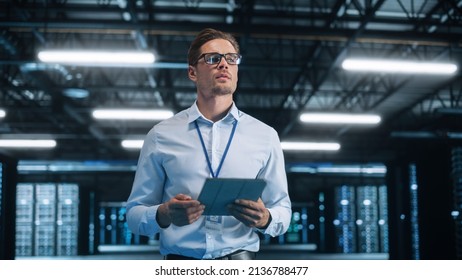 Caucasian Data Center IT Technician Standing at the Server Rack Corridor with a Tablet Computer. He is Visually Inspecting Something while Looking Away. Night Office Concept - Powered by Shutterstock