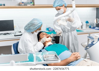 Caucasian dentist examine tooth for young man patient at dental clinic. Attractive male lying on dental chair, get dental treatment from female doctor during procedure appointment service in hospital. - Powered by Shutterstock