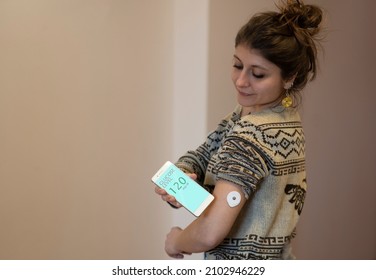 Caucasian Diabetics Patient Checking Glucose Level With A Remote Sensor And Smartphone. Continuous Monitoring Glucose Levels Without Blood Using Digital Glucose Meter.