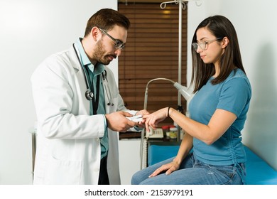 Caucasian Doctor Checking The Blood Oxygen Levels Of A Latin Young Woman With An Oximeter 