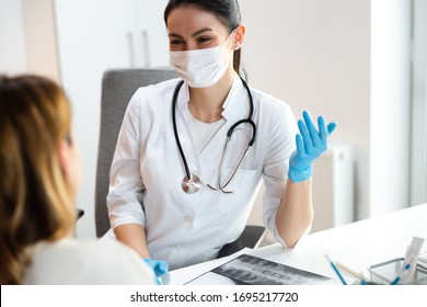 Caucasian Doctor In Medical Mask Speaking With Mother About Scoliosis Of Her Daughter Stock Photo. Pediatrics Concept