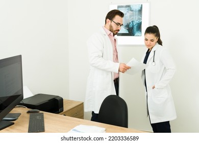 Caucasian Doctor And Radiologist Talking About The Test Results Of A Patient While Looking At The X-ray Images At Their Office 