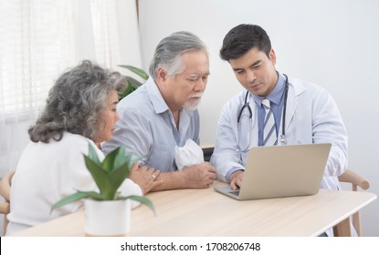 Caucasian doctor use laptop and talk with old asian male patient about disease symptom, elderly health check up at home.