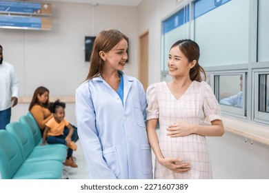 Caucasian doctor walking with pregnant woman in the hallway in hospital. Attractive female professional medic work and give medical examination to enceinte woman in corridor of health medical clinic. - Powered by Shutterstock