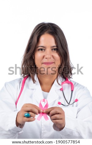 Caucasian doctor woman with pink stethoscope holding breast cancer pink ribbon on a white background.