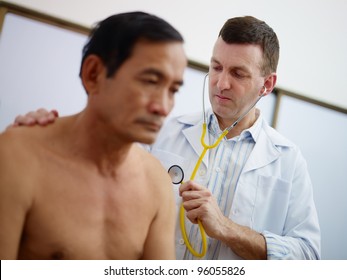 Caucasian Doctor Working And Visiting Old Asian Male Patient In Hospital With Stethoscope