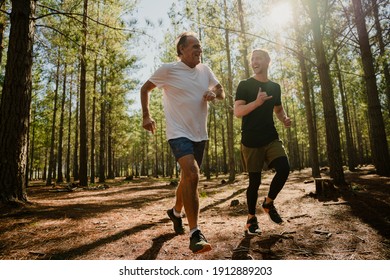 Caucasian Elderly Father And Active Son Running In Forest Determined To Exercise 