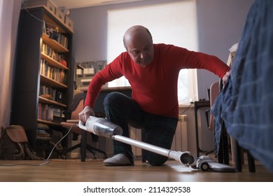 Caucasian Elderly Man Vacuums Under The Bed, Does A Cleaning Of The House.