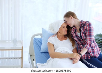 Caucasian Elderly Mother In White Headscarf Is Laying On Bed In Hospital After Chemotherapy Because She Is Suffering From Cancer Or Leukemia Patient And Young Daughter Is Hugging And Caring Her Mom.