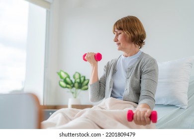 Caucasian Elderly Patient Woman Sitting On Bed And Lifting Dumbbell To Exercise After Treatment In Hospital. Workout Exercise For Recovery. Healthcare Medical And Physiotherapist Insurance Concept