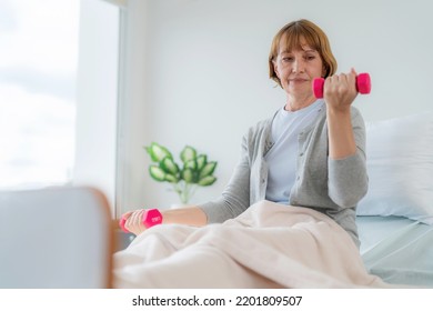 Caucasian Elderly Patient Woman Sitting On Bed And Lifting Dumbbell To Exercise After Treatment In Hospital. Workout Exercise For Recovery. Healthcare Medical And Physiotherapist Insurance Concept