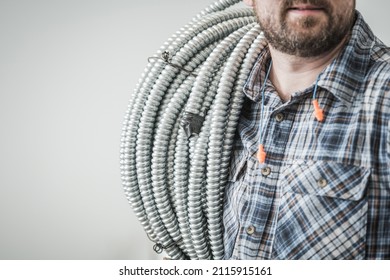 Caucasian Electric Construction Worker in His 30s with Conduit Pipe on His Shoulder Close Up. Industrial Theme.