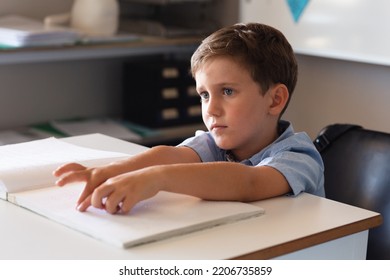 Caucasian elementary schoolboy studying on braille at desk in classroom. unaltered, education, childhood, blindness, disability, studying and school concept. - Powered by Shutterstock