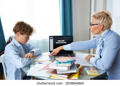 caucasian english teacher woman helps boy learn lessons at home, tutor helps schoolboy learn lessons, checks the child's homework. individual home-based quarantine - Shutterstock ID 1818846860