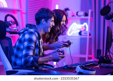 Caucasian Esport couple gamer playing online video game on computer. Handsome man gaming player feel happy and excited, enjoy technology broadcast live streaming while plays cyber tournament at home - Powered by Shutterstock