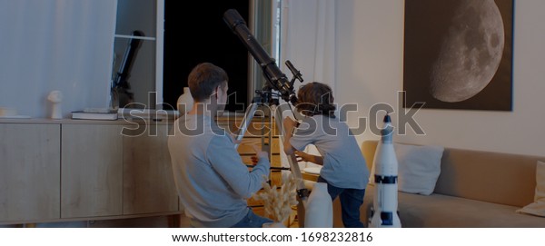 Caucasian family\
- father and son, using telescope to explore moon surface. Stay\
home, learning from home,\
quarantie