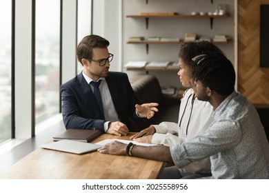 Caucasian Family Financial Advisor Consulting To Young 30s African Couple During Meeting In Bank Office. Realtor Communicates To Spouses About Tenancy. Loan And Mortgage, Real Estate Purchase Concept