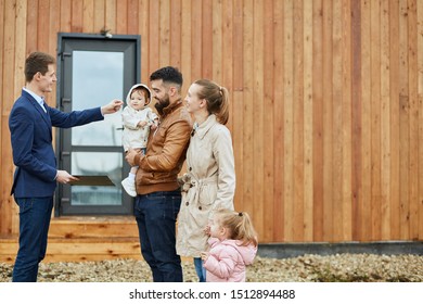 Caucasian family of four stand outdoor near new house just sold. Realtor give them keys. - Shutterstock ID 1512894488