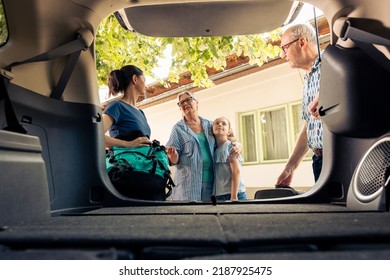 Caucasian family going on seaside holiday with luggage and bags, loading baggage in automobile trunk. Little girl with mother and grandparents travelling on vacation trip with vehicle. - Powered by Shutterstock