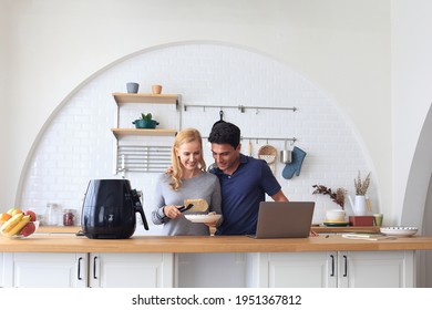 The Caucasian family Make breakfast with the air fryer together. Husband and wife Cooking in the kitchen together at home. Men working from home. Happy couple relationship and technology concept - Shutterstock ID 1951367812