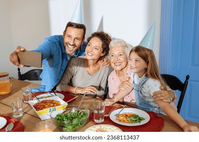 Caucasian family is seated around the table, celebrating grandmas birthday and taking a selfie together - Shutterstock ID 2368113437