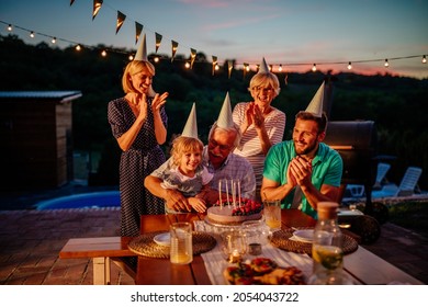 Caucasian family sitting together in the backyard, clapping for a birthday singing birthday song and enjoying life.