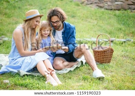caucasian family using digital tablet during picnic at countryside