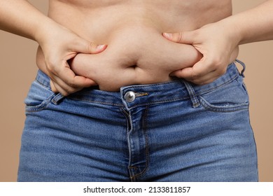 Caucasian fat woman touching overweighted belly with hands wearing blue jeans. Visceral fat. Body positive and accepting yourself. Sudden weight gain. Tight little clothes. Need for wardrobe change.