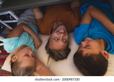 Caucasian Father With Daughter And Son Smiling, Lying In Blanket Fort At Home. Family Enjoying Quality Free Time Together.