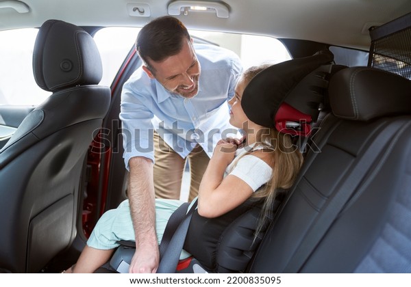 Caucasian\
father securing daughter into baby car\
seat