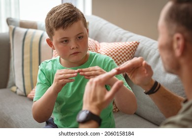 Caucasian father and son communicating using sign language while sitting on the couch at home. sign language learning concept - Powered by Shutterstock