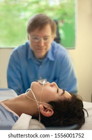 Caucasian Father Watching Over Biracial Disabled Son In Hospital Recovery Room Post Operation, With Breathing Tube Down Throat