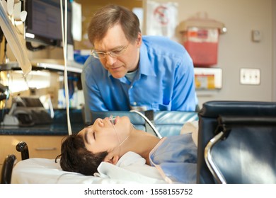 Caucasian Father Watching Over Biracial Disabled Son In Hospital Recovery Room Post Operation, With Breathing Tube Down Throat