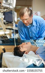 Caucasian Father Watching Over Biracial Disabled Son In Hospital Recovery Room Post Operation, With Breathing Tube Down Throat