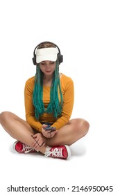 Caucasian Female with African American Dreadlocks Listens Music in Headphones On Cellphone Smartphone While Posing in Streetwear Clothing Over White. Vertical image Orientation