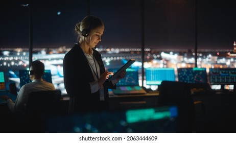 Caucasian Female Air Traffic Controller Working on Tablet in Airport Tower. Office Room is Full of Desktop Computer Displays with Navigation Screens, Airplane Flight Radar Data for the Team.