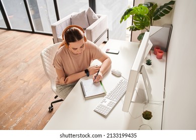 Caucasian Female With Arm Implant Sitting At The Table With Her Computer And Writing