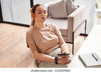 Caucasian Female With Arm Implant Sitting At The Table With Her Smartphone In Hands