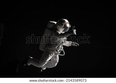 Caucasian female astronaut using her mobile phone during spacewalk, messaging, taking pictures
