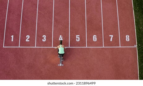 Caucasian female athlete alone on the athletic track, sprint running in line four, aerial directly above view. - Shutterstock ID 2311896499