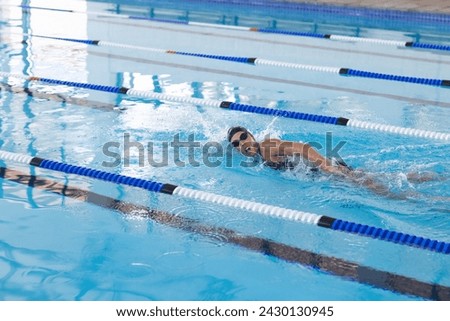 Caucasian female athlete swimmer swimming laps in a pool. Her focused training suggests preparation for a competition or personal fitness goals.