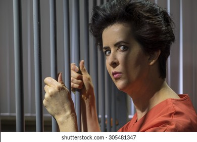 Caucasian Female Behind Bars In A Jail Cell